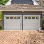 WeServe | A two door garage with white doors that have windows with a brownish roof and a paved driveway with trees in the background