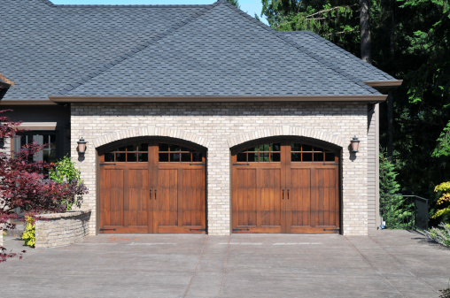 WeServe | Two brown garage doors with a dark grey roof slates and a wide driveway